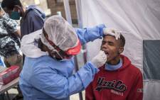 FILE: A Doctors Without Border (MSF) nurse (C) performs a COVID-19 coronavirus test during a Ministry of Health screening and testing drive in the Wolhuter men's hostel in Jeppestown district of Johannesburg, on 14 May 2020. Picture: AFP