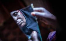 Amran Mahamood, who has made a living for 15 years by circumcising young girls, looks into a piece of a mirror on 19 February, 2014 in Hargeysa. Picture: AFP.