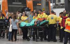 A man lies on a stretcher as emergency personnel gather on a platform beside a train at Estacio de Franca (Franca station) in central Barcelona on 28 July, 2017 after the regional train appears to have hit the end of the track inside the station injuring at least 23 people. Picture: AFP.