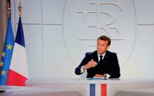 This picture shows a screen displaying French President Emmanuel Macron as he addresses the nation during a televised interview from the Elysee Palace concerning the situation of the novel coronavirus COVID-19 in France, in Paris on 14 October 2020. Picture: AFP
