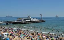 Beachgoers enjoy the sunshine as they sunbathe and play in the sea, backdropped by moored cruise ships, on Bournemouth beach in Bournemouth, southern England, on 25 June 2020. Picture: AFP. 