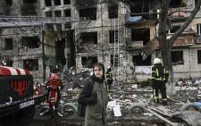 Maksim Korobych stands near firefighters in front of a destroyed apartment building after it was shelled in the northwestern Obolon district of Kyiv on 14 March 2022. Picture: AFP