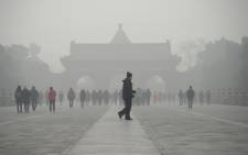 An elderly man walks in front of a group of people during heavy smog at the Temple of Heaven park in Beijing on 20 December, 2016. Picture: AFP.