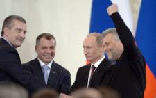 Russia's President Vladimir Putin (2nd R), Crimean Prime Minister Sergei Aksyonov (L), Crimean parliament speaker Vladimir Konstantionov (2nd L) and Alexei Chaly, Sevastopol's new de facto mayor (R), join hands after signing a treaty on the Ukrainian Black Sea peninsula becoming part of Russia in the Kremlin in Moscow . Picture: AFP.