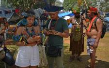 Digital indigenous activists Tukuma Pataxo (2-L), of the Pataxo tribe, and Samela Awia (L), of the Satere Mawe Amazonian tribe, check their social media posts on their mobile phones at the Terra Livre Indigenous Camp in Brasilia on April 7, 2022. Picture: Carl de Souza / AFP