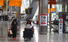 Passengers push their luggage past signage displaying the way to a COVID-19 test centre, in Terminal 5 at Heathrow airport in London, on 3 June 2021. Picture: DANIEL LEAL-OLIVAS/AFP