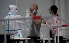 A health worker takes a swab sample on a man to be tested for COVID-19 coronavirus at a swab collection site along a street in Beijing on 25 April 2022. Picture: Noel Celis/AFP