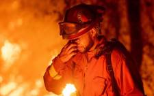 FILE: An inmate firefighter pauses during a firing operation in Redding, California on 27 July 2018.  The blaze on 28 October 2019, the largest of more than a dozen wildfires burning throughout the state, has destroyed dozens of homes and vineyards, including the renowned 150-year-old Soda Rock Winery. Picture: AFP.