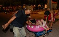 People tend to an injured woman at the Formosa Fun Coast amusement park after an explosion in the Pali district of New Taipei City in Taiwan on 27 June 2015. Picture: AFP.