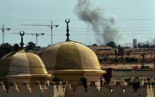FILE: Smoke rises behind a mosque as NATO planes bombard troop positions close to the eastern gate of the city of Sirte. Picture: AFP