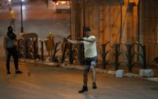 A Palestinian youth throws stones during clashes with Israeli security forces in the city center of the occupied West Bank town of Hebron on April 25, 2021, following a protest in support of Palestinian demonstration in Israeli-annexed east Jerusalem. Picture: Hazem Bader / AFP.