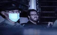 This file photo taken on November 10, 2014 shows British banker Rurik Jutting (R), charged with the grisly murders of two Indonesian women, smiling as he sits in a prison van leaving the eastern court in Hong Kong. Picture: AFP.