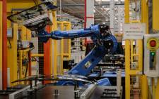 A robot arm carries a glass part in the assembly line of a factory. Picture: AFP