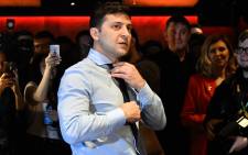 Ukrainian comic actor, showman and presidential frontrunner Volodymyr Zelensky surrounded by cameramen and photographers adjusts his tie as he plays table tennis with a journalist ahead of the provisional results at the headquarter in Kiev on March 31, 2019. Picture: AFP.
