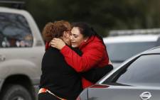 Vanessa Flores (R) embraces another woman after she leaves the locked down Veterans Home of California during an active shooter turned hostage situation on 9 March 2018 in Yountville, California. Picture: AFP.