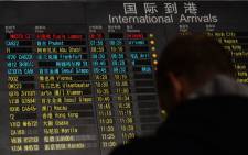 FILE: A man stands beside the arrival board showing the flight MH370 (top-red) at the Beijing Airport after news of the Malaysia Airlines Boeing 777-200 plane disappeared on 8 March 2014. Picture: AFP.