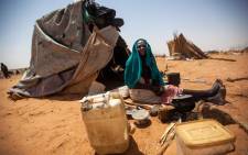 A handout picture released by the United Nations-African Union Mission in Darfur (UNAMID) on 28 May 2014 shows Aisha Abdala, a displaced woman from Katila, South Darfur, cooking next to her shelter at the al-Sereif camp for Internally Displaced Persons (IDP) in Nyala, South Darfur. Picture: AFP.