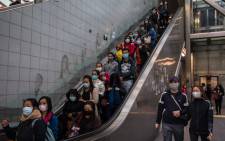 People wearing protective face masks use an escalator in Hong Kong on 9 February 2020, as a preventative measure after a coronavirus outbreak which began in the Chinese city of Wuhan. Picture: AFP
