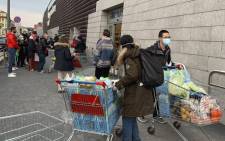 People using protective masks leave a supermarket with trolleys full of shopping in Milan on 8 March 2020 as Italy quarantines more than 10 million people around the financial capital Milan and the tourist mecca Venice for nearly a month to halt the spread of the novel coronavirus, COVID-19. Picture: AFP