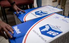 An electoral commission official verifies sealed ballot boxes at the Fordsburg Primary School polling station under the supervision of party delegates in Johannesburg on 1 November 2021. Picture: Emmanuel Croset/AFP