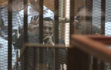 FILE:Egypt’s deposed president Hosni Mubarak waves from behind the accused cage during his trial on 21 May, 2014 in Cairo. Picture: AFP.