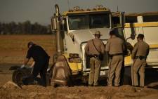Investigators and California Highway Patrol Border Division officers look over the scene of a crash between an SUV and a semi-truck full of gravel near Holtville, California on March 2, 2021. Picture: Patrick T. Fallon / AFP. 