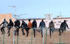 In this file photo taken on 19 February, 2015 migrants sit atop a border fence separating Morocco from the north African Spanish enclave of Melilla in the first attempt to jump since the camp on Mount Gurugu burned down. Picture: AFP