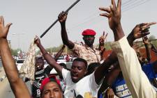 FILE: Sudanese men chant slogans as a soldier imitates President Omar al-Bashir waving his trademark cane, on 11 April 2019 during a rally in the capital Khartoum. Picture: AFP.