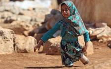 In this file photo taken on 20 June 2018 eight-year-old Maya Mohammad Ali Merhi walks using prosthetic legs made by her father from tin cans in a camp for displaced people, in the northern Syrian province of Idlib. Picture: AFP.