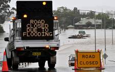 Officials block off flooded roads next to the old Windsor Bridge, along the overflowing Hawkesbury River in the northwestern Sydney suburb of Windsor on 4 July 2022. Picture: SAEED KHAN/AFP