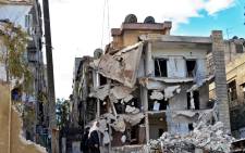 FILE: An image made available 27 February 2014 showing civilians walking by a building destroyed by government launched barrel bomb strikes in the Aleppo neighbourhood of Ansari, Aleppo, Syria, 26 February 2014. Picture: EPA.