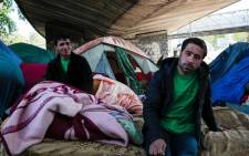 Mounir (R), a 28-year-old man from Pakistan, sits on a mattress under a bridge at a migrant and refugee makeshift camp set up under the highway near Porte de la Chapelle, northern Paris, on 19 April 2017. Picture: AFP.