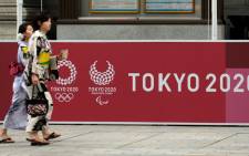 FILE: Pedestrians walk in front of a board displaying the Tokyo 2020 logos for the upcoming Tokyo 2020 Olympic Games on 23 July 2019, nearly one year before the start of the Tokyo 2020 Olympic Games. Picture: AFP