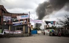 Electoral banners are seen as smoke rises from a fire at the independent national electoral commission's (CENI) warehouse on 13 December 2018 in Kinshasa, ten days ahead of presidential elections that have been foreshadowed by violence. Picture: AFP
