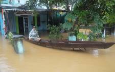 In this picture taken on 5 November 2017 a man sits on a boat in front of his flooded home in Hoa Vang district, central city of Danang following the passage of the typhoon Damrey on central Vietnam. Picture: AFP.