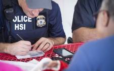 FILE: This image released by the US Immigration and Customs Enforcement (ICE) shows a Homeland Security Investigations (HSI) officer checking an identity document on 7 August 2019. Picture: AFP