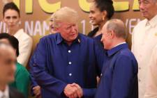President Donald Trump shakes hands with Russia’s President Vladimir Putin as they pose for a group photo ahead of the Asia-Pacific Economic Cooperation Summit leaders gala dinner in the central Vietnamese city of Danang on 10 November 2017. Picture: AFP.