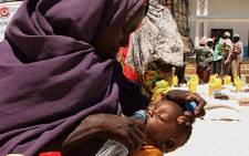 An internally displaced woman from Southern Somalia gives water to her daughter at a distribution centre. Picture: AFP