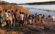 Victims of Cyclone Idai stand in line to receive food and water from the relief boats next to the Buzi River. Picture: Christa Eybers/EWN