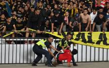 This file photo taken on 5 September 2019 shows policemen detaining a supporter of Indonesia next to supporters of Malaysia (in black) after an incident during their 2022 Qatar World Cup preliminary qualification round 2 football match at the Gelora Bung Karno stadium in Jakarta. Picture: AFP