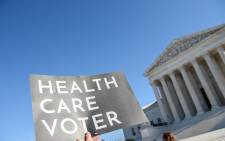 FILE: A demonstrator holds a sign in front of the US Supreme Court in Washington, DC, on 10 November 2020 as the high court opened arguments in the long-brewing case over the constitutionality of the 2010 Affordable Care Act. Picture: AFP. 