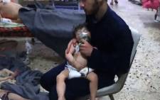An image grab taken from a video released by the Syrian civil defence in Douma shows unidentified volunteers giving aid to children at a hospital following an alleged chemical attack on the rebel-held town on 8 April 2018. Picture: AFP.