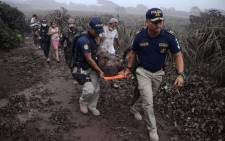 Police officers carry a wounded man after the eruption of the Fuego Volcano, in El Rodeo village, Escuintla department, 35 km south of Guatemala City on 3 June, 2018. Picture: AFP.