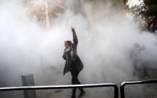 An Iranian woman raises her fist amid the smoke of tear gas at the University of Tehran during a protest driven by anger over economic problems, in the capital Tehran on 30 December, 2017.  Picture: AFP