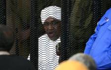 FILE: Sudan's deposed military ruler Omar al-Bashir sits in a defendant's cage during his corruption trial in Khartoum on 24 August 2019. Picture: AFP