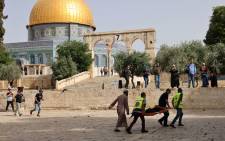 Palestinian medics walk near the Dome of the Rock as they evacuate on a stretcher a wounded protester from the Aqsa mosque compound in Jerusalem's Old City on 10 May 2021, amidst clashes with Israeli security forces.Picture: Ahmad Gharabli/AFP