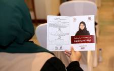 A woman holds a leaflet for the candidate for Qatar’s Shura council elections in the 17th constituency, Leena Nasser al-Dafa, during a campaign event in Doha, on September 26, 2021, ahead of Qatar's inaugural legislative polls. Picture: AFP