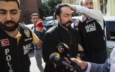 FILE: In this file photo taken on July 11, 2018 Turkish police officers escort televangelist and leader of a sect, Adnan Oktar (C) in Istanbul, as he is arrested on fraud charges. Picture: AFP