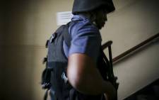 A member of the Saps Tactical Response Team makes his way up some stairs into a hostel during a raid in Bellville's CBD, Cape Town. Picture: Thomas Holder/EWN