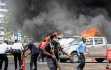 People extinguish fires on cars caused by a bomb explosion near Parliament building in Kampala, Uganda, on 16 November 2021. Picture: Ivan Kabuye/AFP